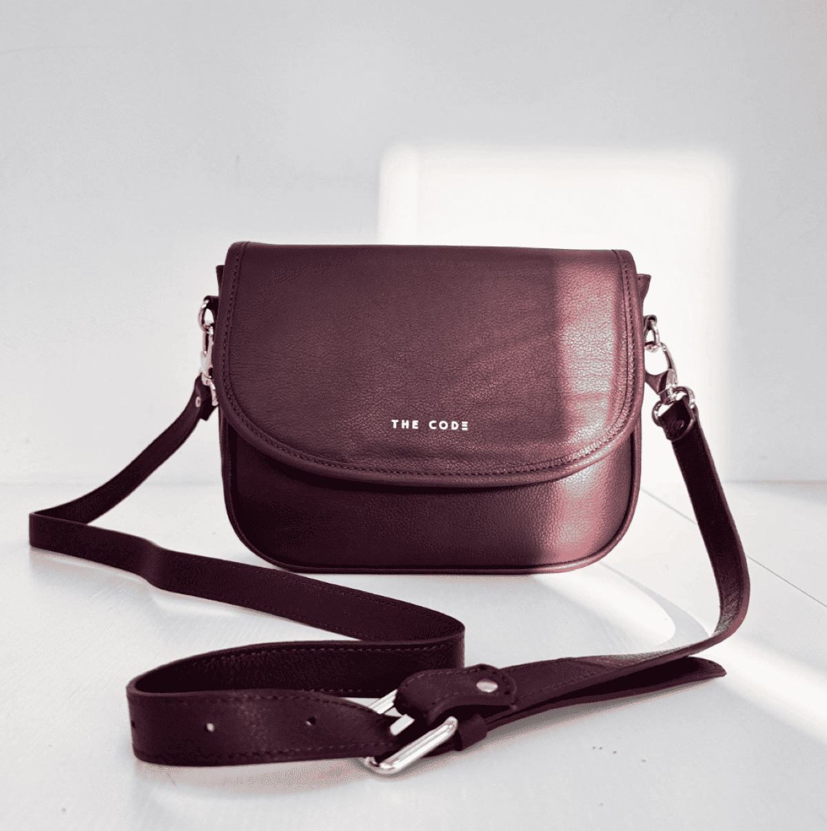 Detalle del bolso Claudia burdeos de The Code, piel natural, cremallera metálica y asa ajustable tipo bandolera.