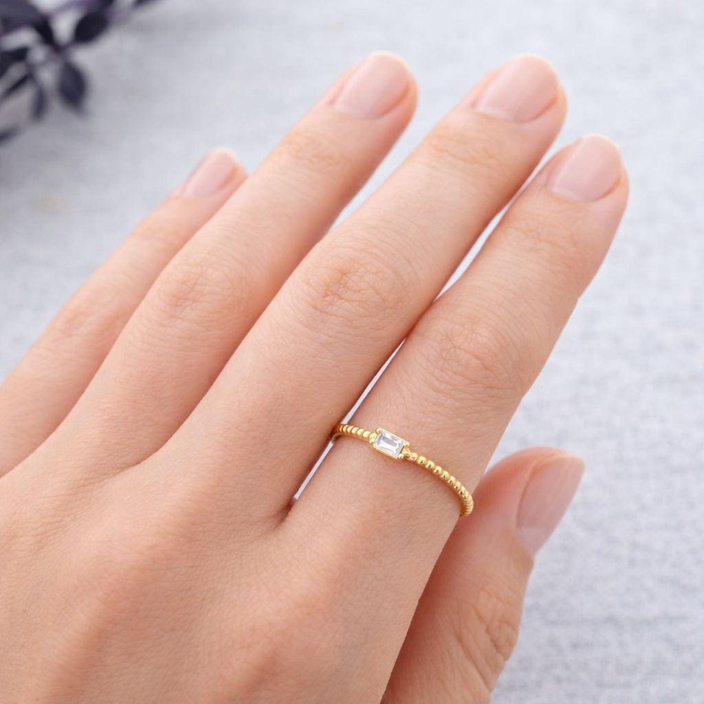 Anillo Blanca ajustable de acero dorado con circonita blanca rectangular mostrado en la mano