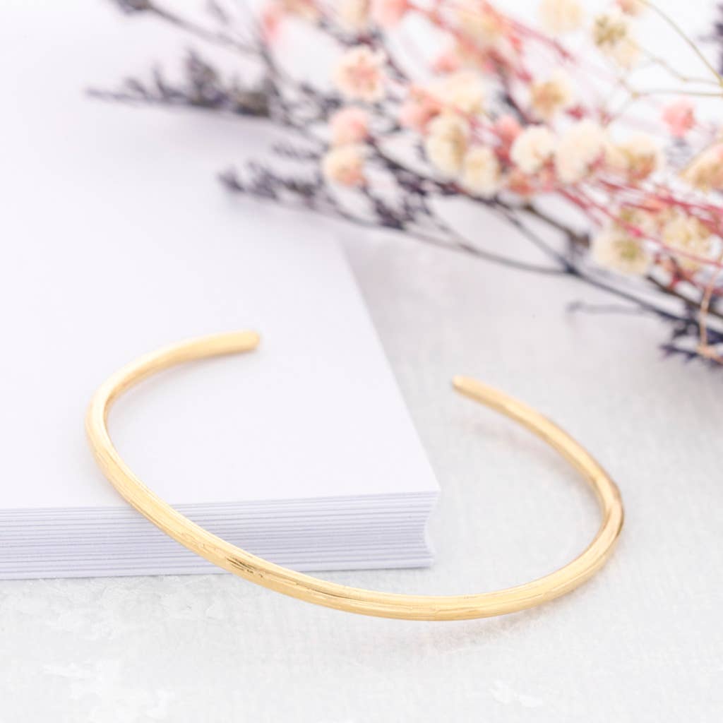 Pulsera Noa rígida de acero dorado mate con diseño abierto y textura irregular