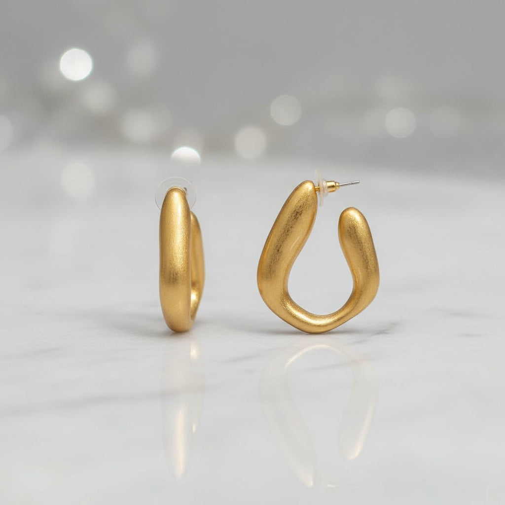 pendientes dorados mate con diseño de aro irregular sobre fondo neutro