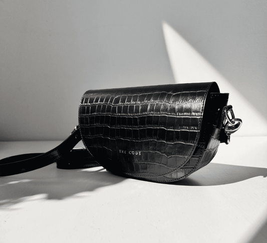Bolso bandolera Alma negro coco de The Code, diseño de media luna en piel grabada, elegante y artesanal. Treinta&tantos showroom.