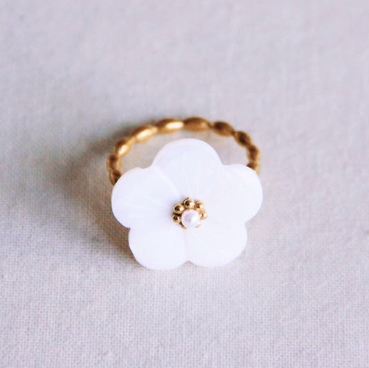 Anillo Liria de acero dorado con aro retorcido y flor blanca nacarada