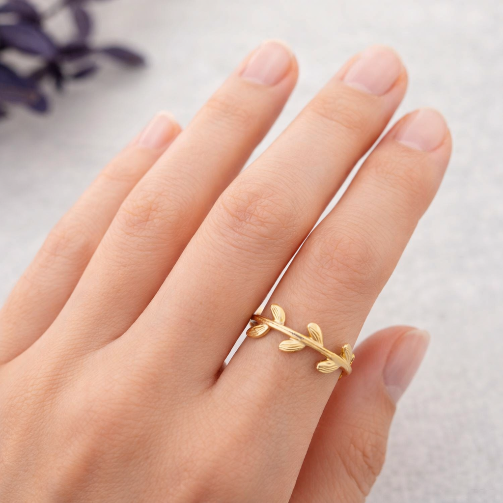 Anillo Lyra de acero dorado mate con diseño botánico de hojas labradas mostrado en la mano