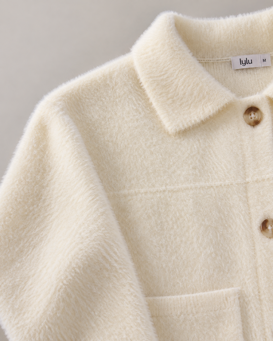 Detalle de chaqueta Calviá blanco roto con bolsillo, puño abotonado y botones efecto carey
