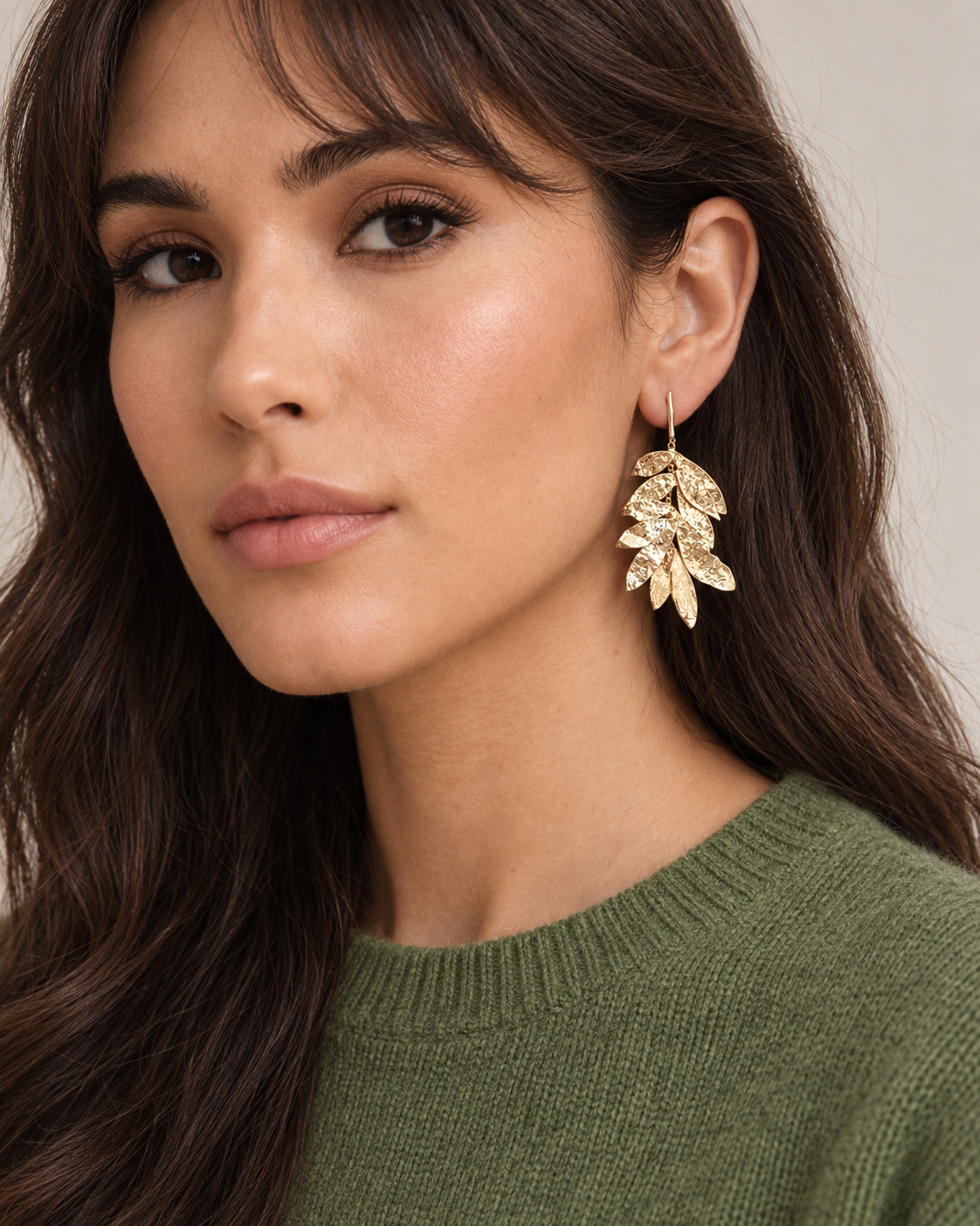 Foto del pendiente puesto
modelo con pendientes largos dorados de hojas martilladas laurus